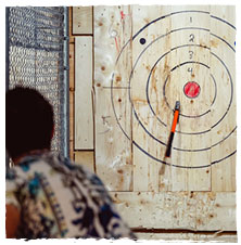 Man finishes throwing an axe at an axe throwing target and misses the bullseye