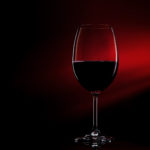 Glass of red wine on black to red gradient background. Concept studio shot.